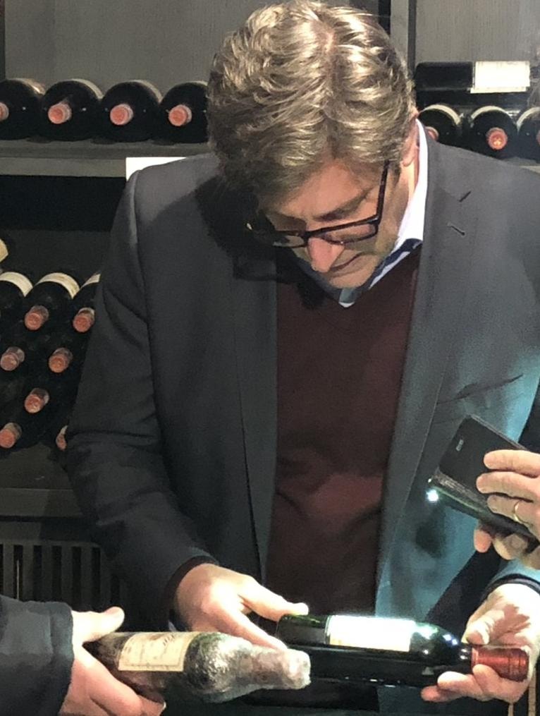 Allan Frischman examining wine bottles in a cellar